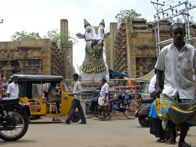Straatbeeld bij tempel met groot Nandi-stierbeeld, riksja’s en voetgangers tijdens Route Zuid India.