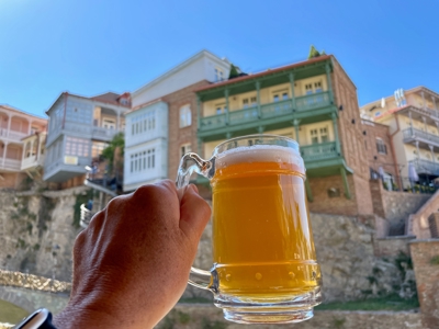 Bierpul in de hand met uitzicht op traditionele balkons en oude huizen in Tbilisi, Georgië.