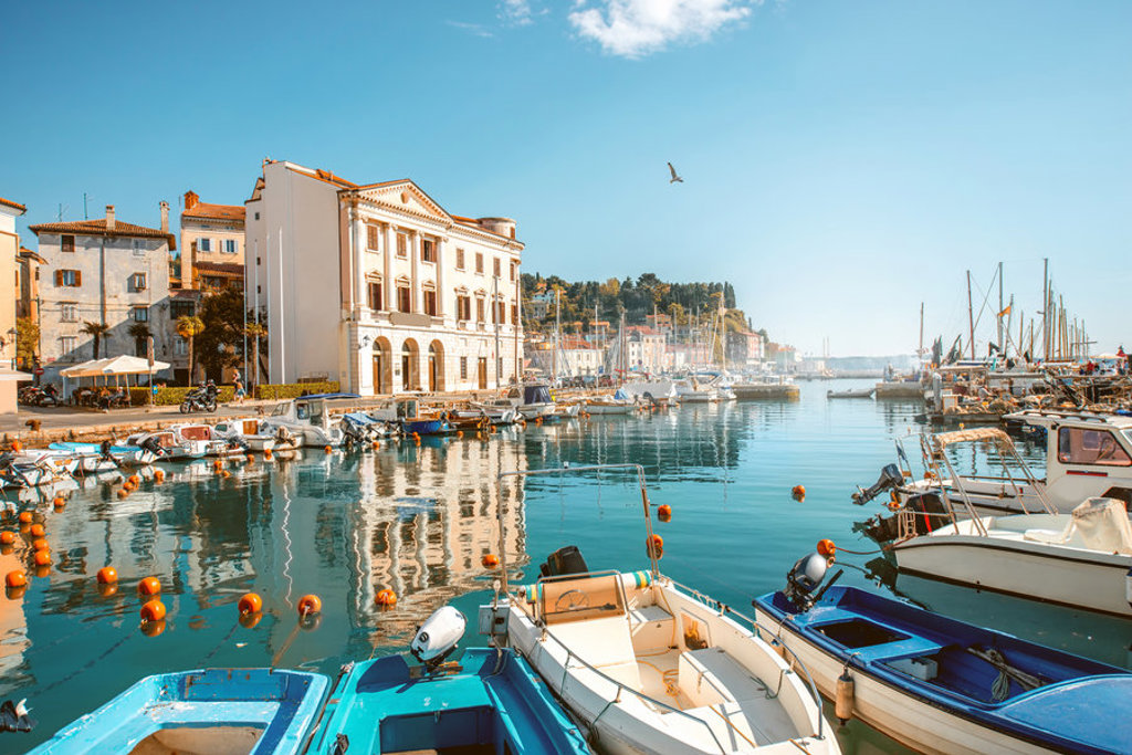 Haven van Piran in Slovenië met kleurrijke bootjes en historische gebouwen aan de kade.