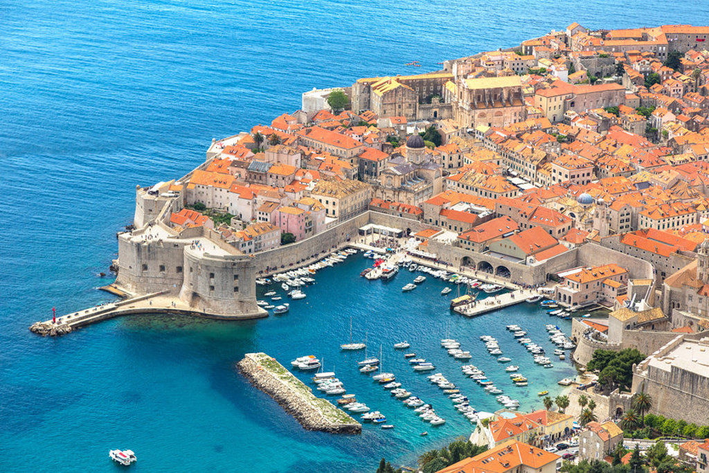 Uitzicht op de ommuurde oude stad Dubrovnik met haven en boten aan de Adriatische Zee, tijdens groepsrondreis Balkan.