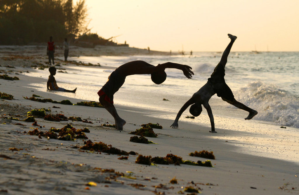 Kinderen maken salto’s op het strand bij zonsondergang op Zanzibar tijdens een familiereis Kenia, Tanzania & Zanzibar.