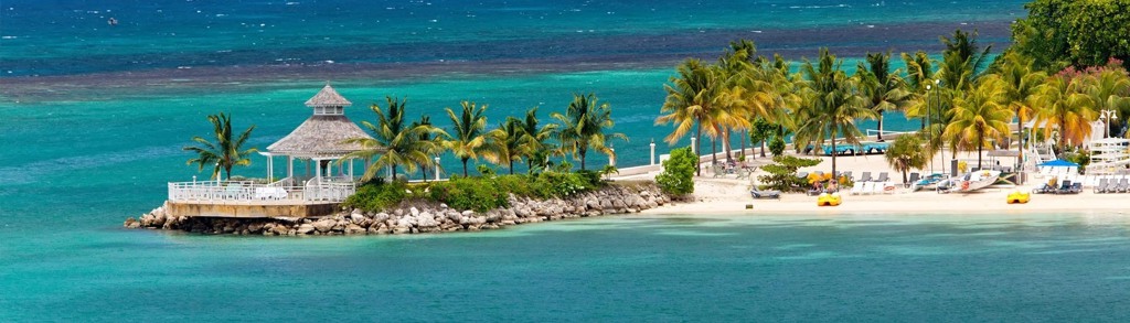 Tropisch strand op Jamaica met palmbomen, turquoise zee en paviljoen aan de kust.