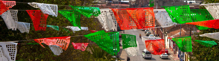 Gekleurde Mexicaanse vlaggetjes boven een straat, passend bij een familiereis naar Mexico.