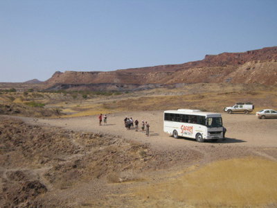 Safaribus met reizigers tijdens rondreis door het Zuidelijk Afrika, geparkeerd in droog berglandschap.