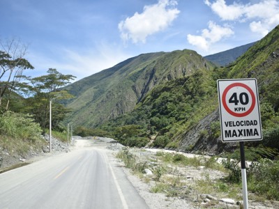 Bergweg door groene vallei in Guatemala met verkeersbord “40 KPH velocidad máxima”.