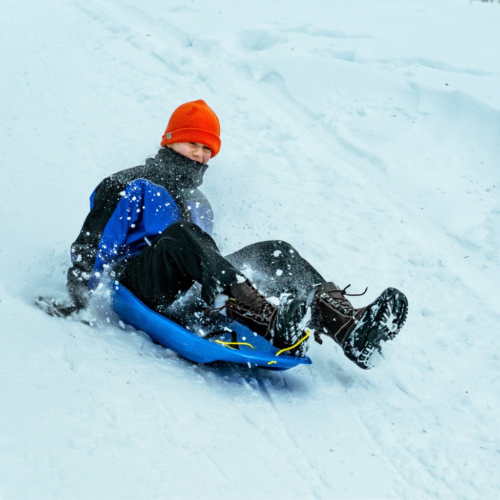 Kind op slee in de sneeuw tijdens familiereis Lapland Winter in Finland.