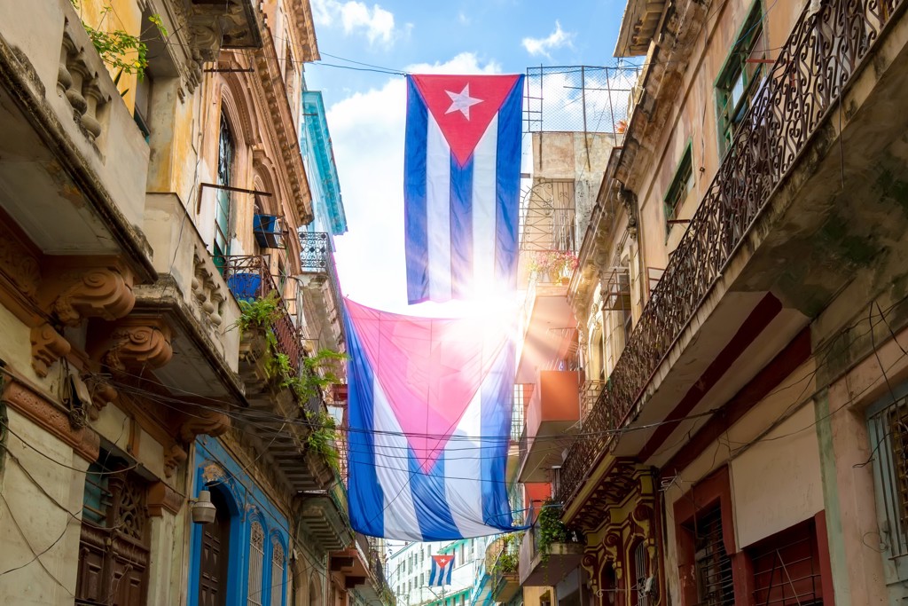 Cubaanse vlaggen hangen tussen kleurrijke gebouwen in een straat in Havana, Cuba.