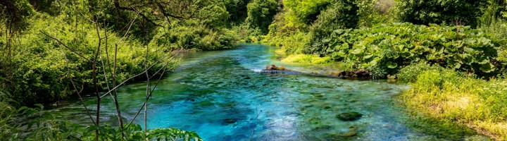 Blauwgroene rivier bij de Blue Eye in Albanië, omringd door groen en bergen.