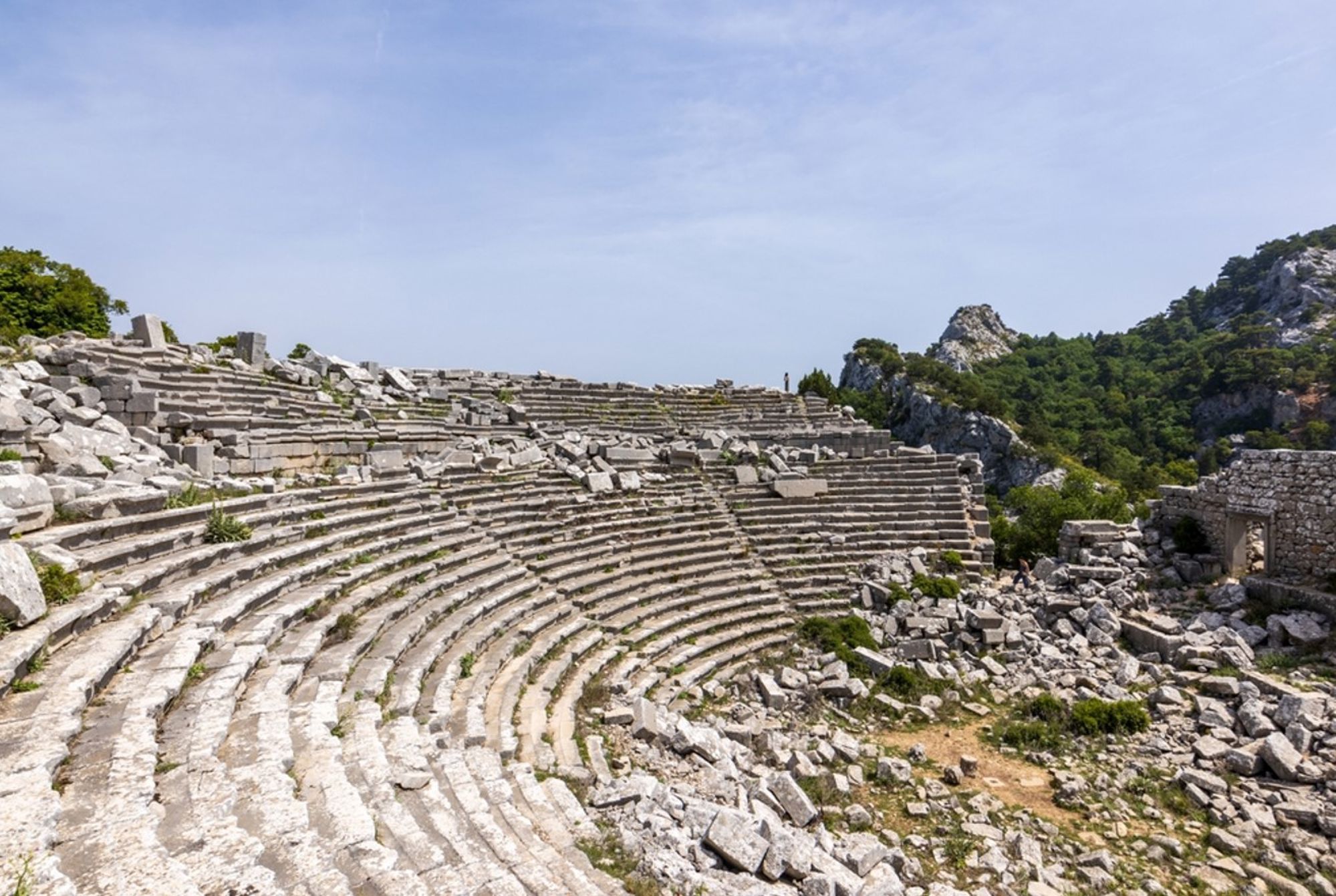 Oud Grieks amfitheater met stenen tribunes tussen rotsen en dennenbossen in Turkije.