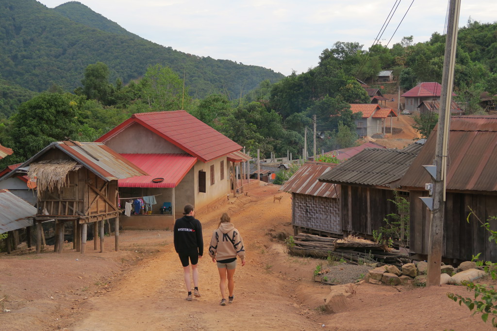 Jonge reizigers wandelen door een bergdorp in Laos tijdens de 22-35ers reis Thailand, Laos & Cambodja.