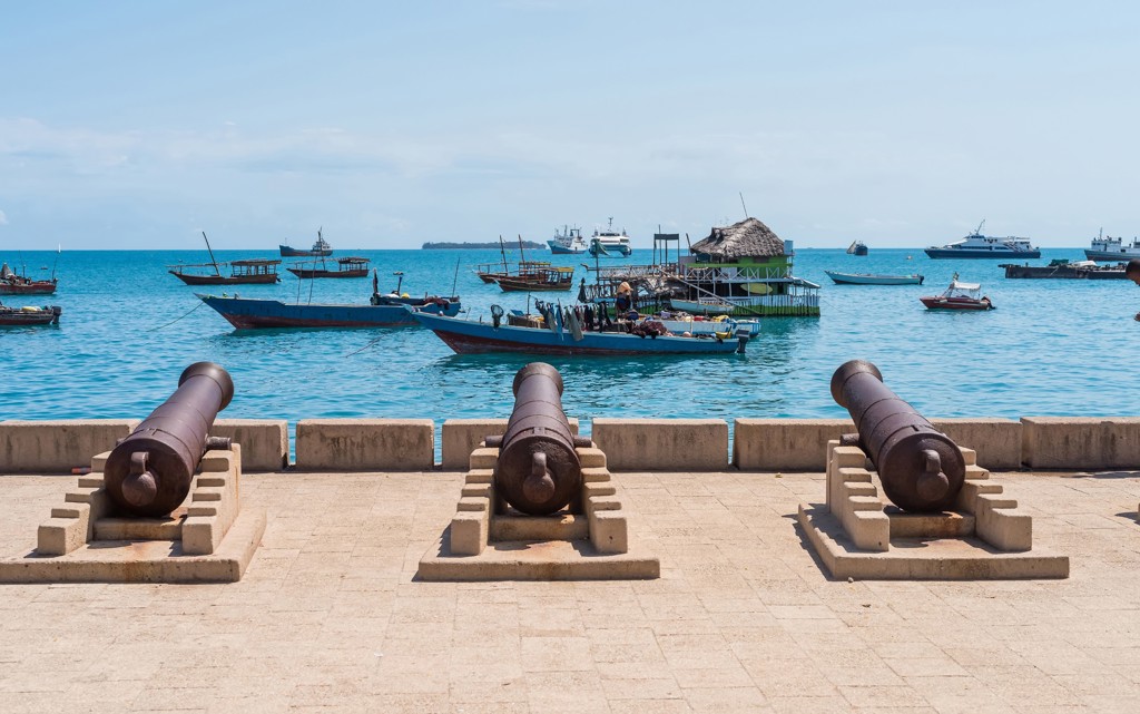 Kanonnen aan de kade met dhowboten in de haven van Stone Town, Zanzibar.