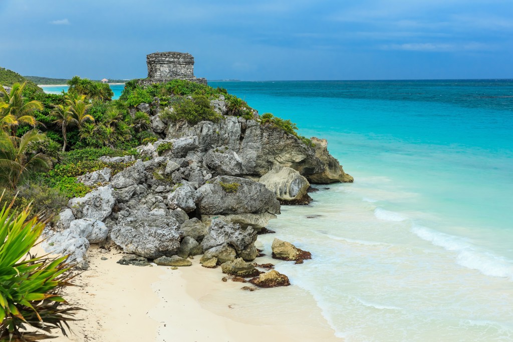 Maya-ruïne op rotsklif bij wit zandstrand en turquoise zee in Tulum, Mexico.