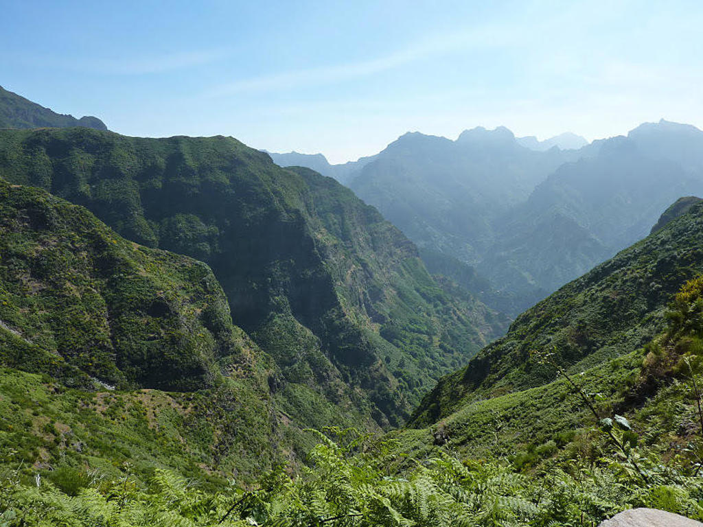 Groene bergvallei en ruige bergtoppen op Madeira, uitzicht tijdens een wandelvakantie.