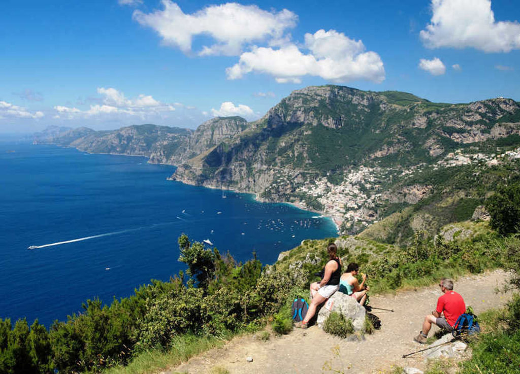 Wandelaars pauzeren met uitzicht op de kliffen en kustplaatsen van de Amalfikust in Italië.
