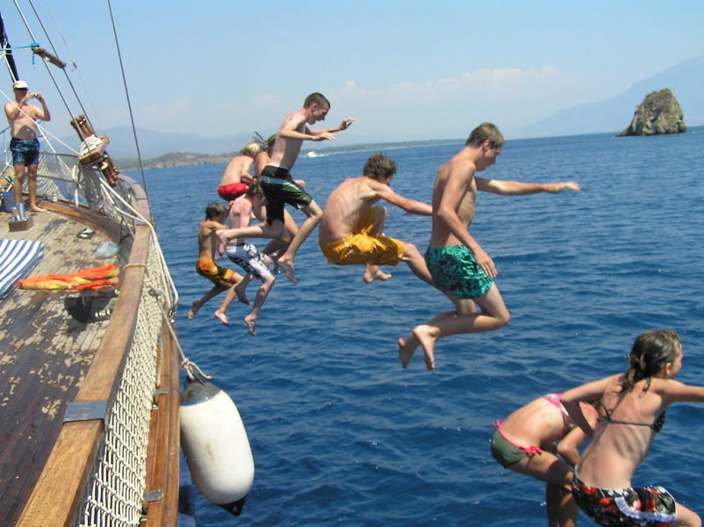 Kinderen springen vanaf een boot de zee in aan de Turkse Turquoise Kust tijdens een familiereis Turkije.