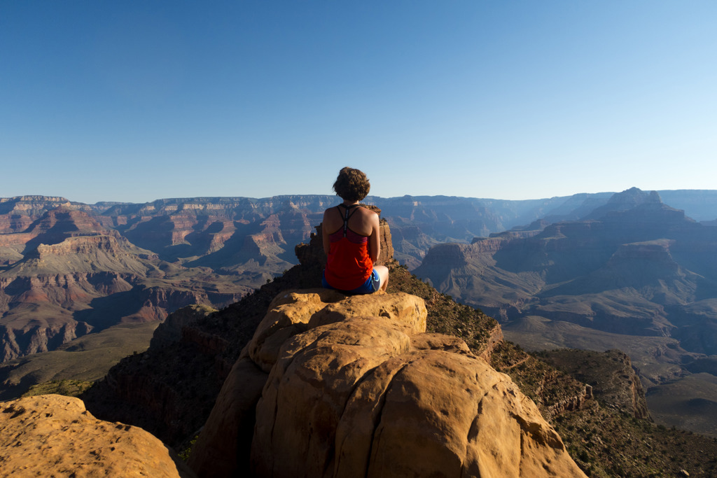 Reiziger op rotsrand met uitzicht over de Grand Canyon in de Verenigde Staten.