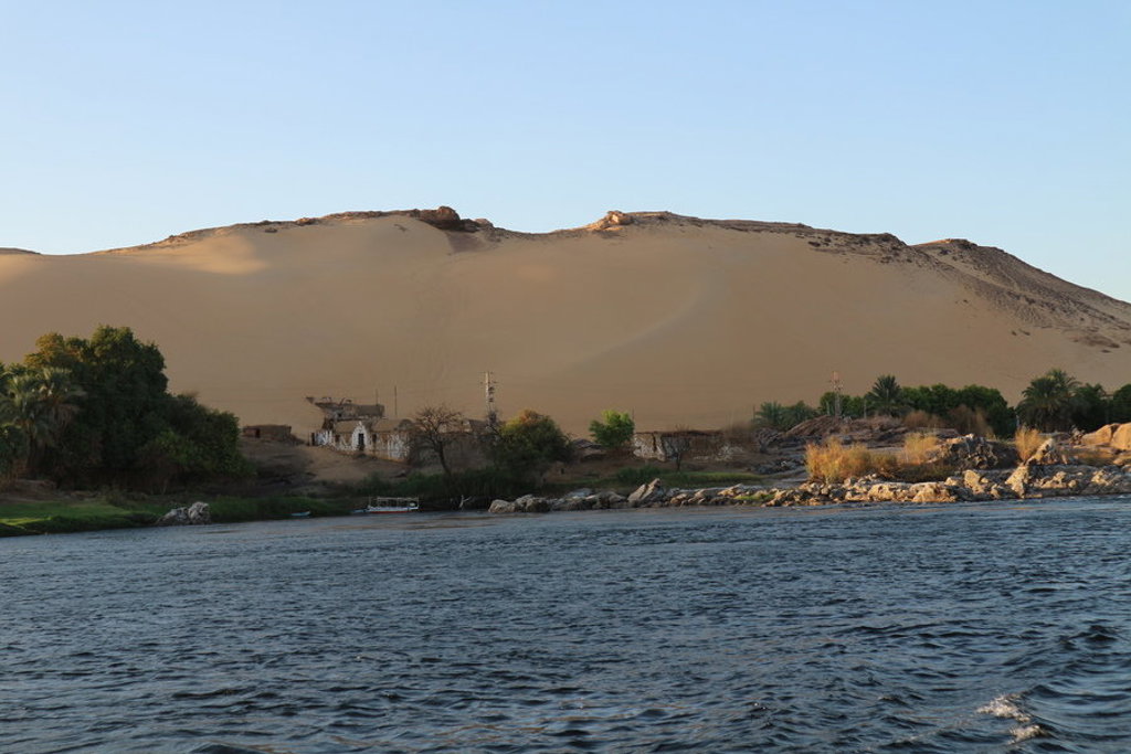 Nijloever met palmbomen en huizen aan de rand van de woestijn, tijdens familiereis Egypte langs de Nijl.