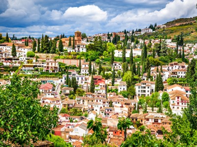 Uitzicht op de witte wijk Albaicín in Granada, Andalusië, met cipressen en terracotta daken.