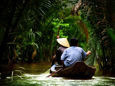 Boottocht door de Mekongdelta in Vietnam, varend door een smalle waterweg tussen palmen.
