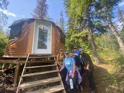 Reizigers bij een yurt in het bos tijdens Route Alaska, dag 16.