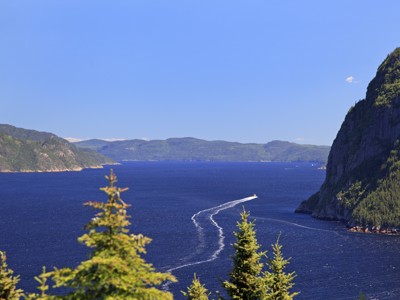 Uitzicht over de Saguenayfjord in Oost-Canada met steile beboste rotswanden en een boot op het water.