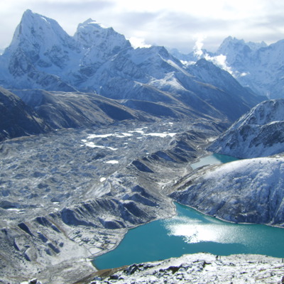 Besneeuwde bergtoppen en gletsjervallei met turquoise gletsjermeer tijdens de Everest-trek in Nepal.