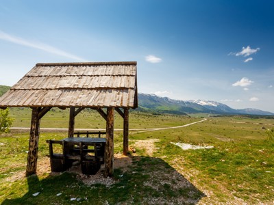 Houten picknickschuilplaats met uitzicht op de bergen en het groene plateau in Bosnië en Herzegovina.