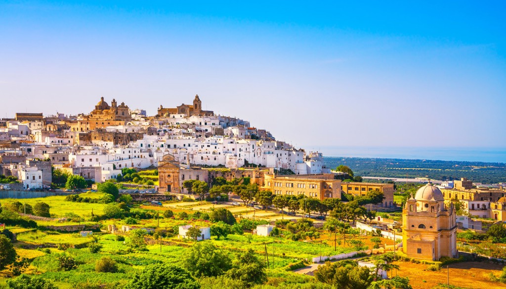Wit heuveldorp in Puglia met uitzicht op olijfgaarden en de Adriatische Zee, Italië.