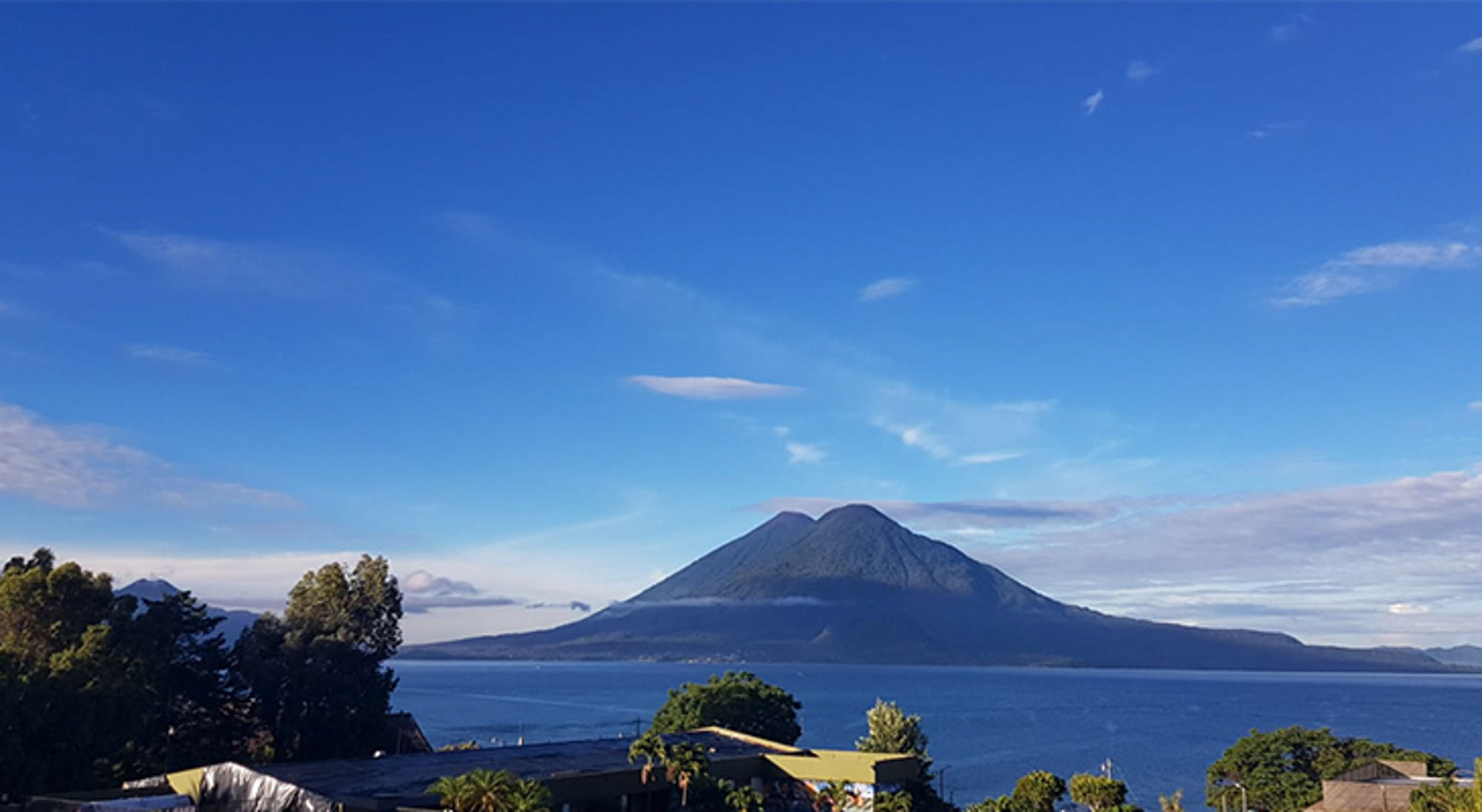 het meer van Atitlán Uitzicht op een vulkaan aan een meer onder een heldere blauwe lucht.
