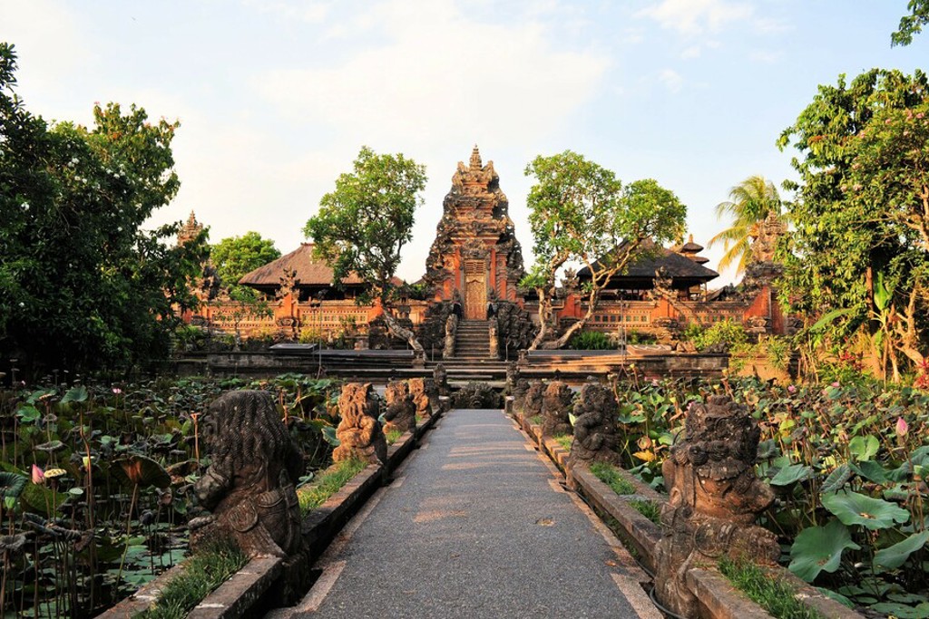 Tempelcomplex op Bali met stenen beelden langs een pad door een lotusvijver, tijdens familiereis Java en Bali.
