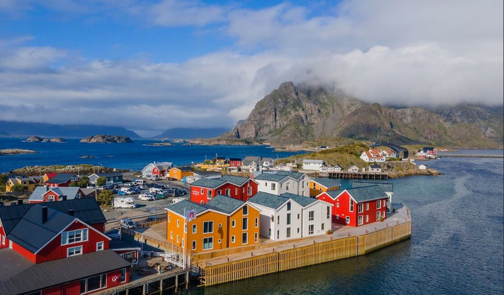 Gekleurde vissershuisjes aan de kust van de Lofoten in Noorwegen, met bergen en zee op de achtergrond.