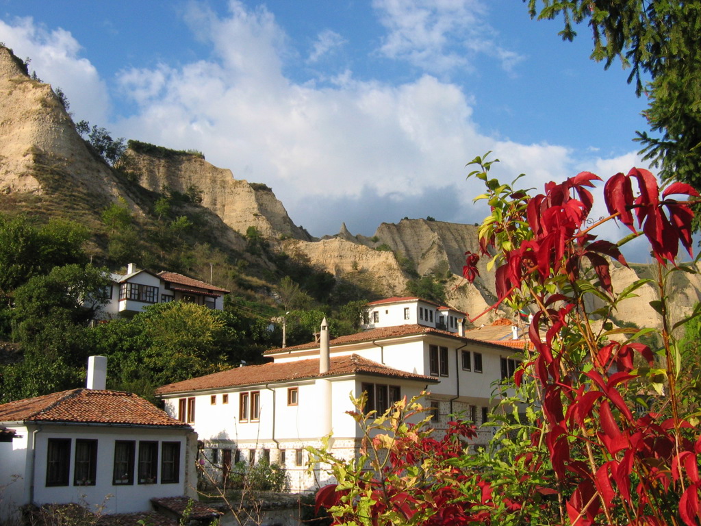 Traditionele huizen in Melnik met zandstenen rotsen op de achtergrond, tijdens een wandelvakantie in Bulgarije.