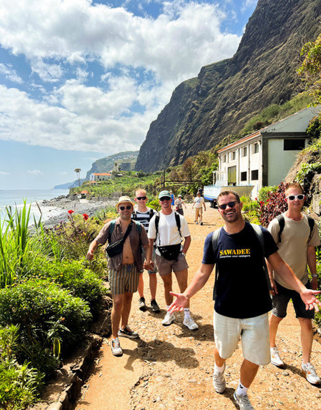 Groep 22-35ers wandelt langs de kust op Madeira, met steile kliffen en zee op de achtergrond.