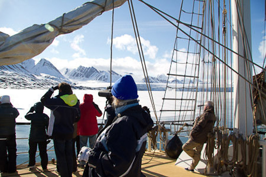 Reizigers op zeilschip Antigua bekijken het ijslandschap en de bergen van Spitsbergen tijdens groepsrondreis.