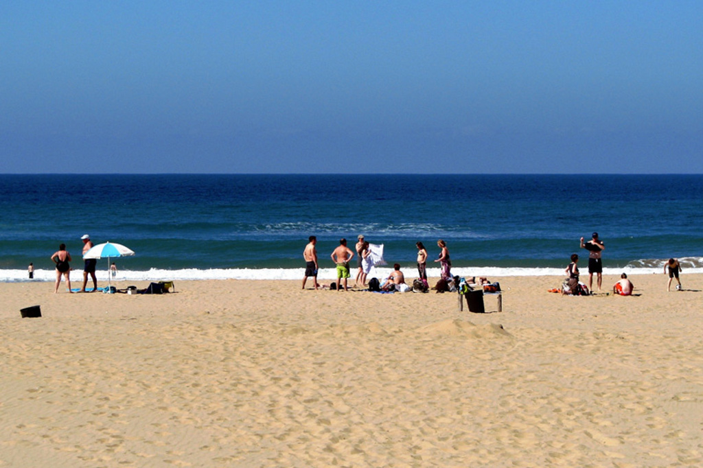 Strand in Zuid-Afrika met reizigers aan zee en golven op de achtergrond.