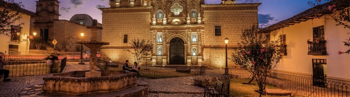 Verlichte kathedraal en fontein op het centrale plein van Cajamarca, Peru, bij zonsondergang.