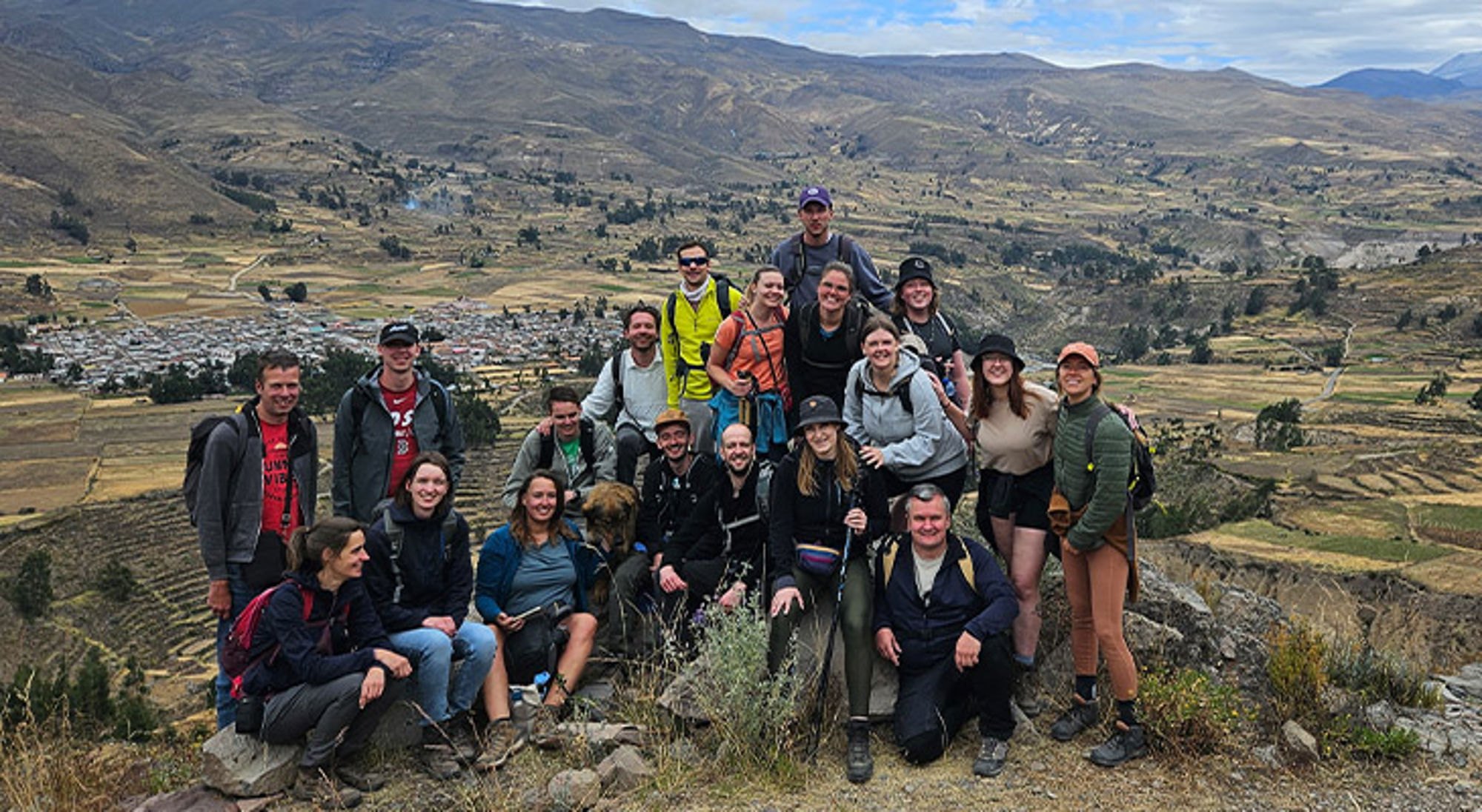 Colca Vallei Groep wandelaars poseert op een bergtop met uitzicht op een vallei en dorp.