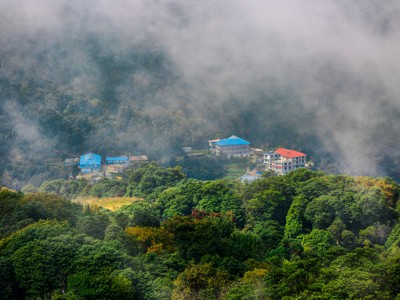 Mistig berglandschap met lodges tussen groene bossen langs de Route Nepal.
