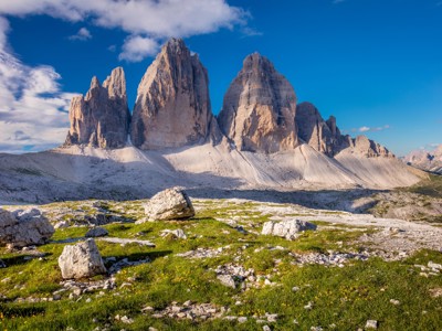 Drei Zinnen in de Dolomieten, Italië, met rotsformaties en alpiene weide onder een blauwe lucht.