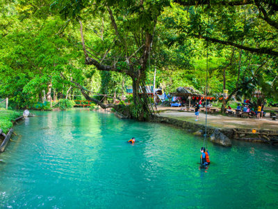 Zwemmen in een helderblauwe rivier met jungle en picknickplek langs de oever, Route Indochina.