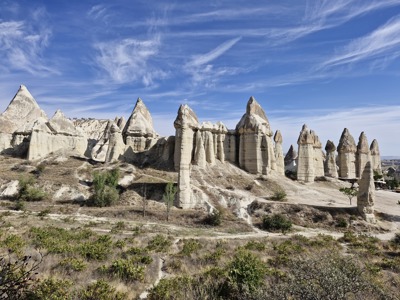 Rotsformaties en feeënschoorstenen in Cappadocië langs de wandelroute, onder een blauwe lucht.
