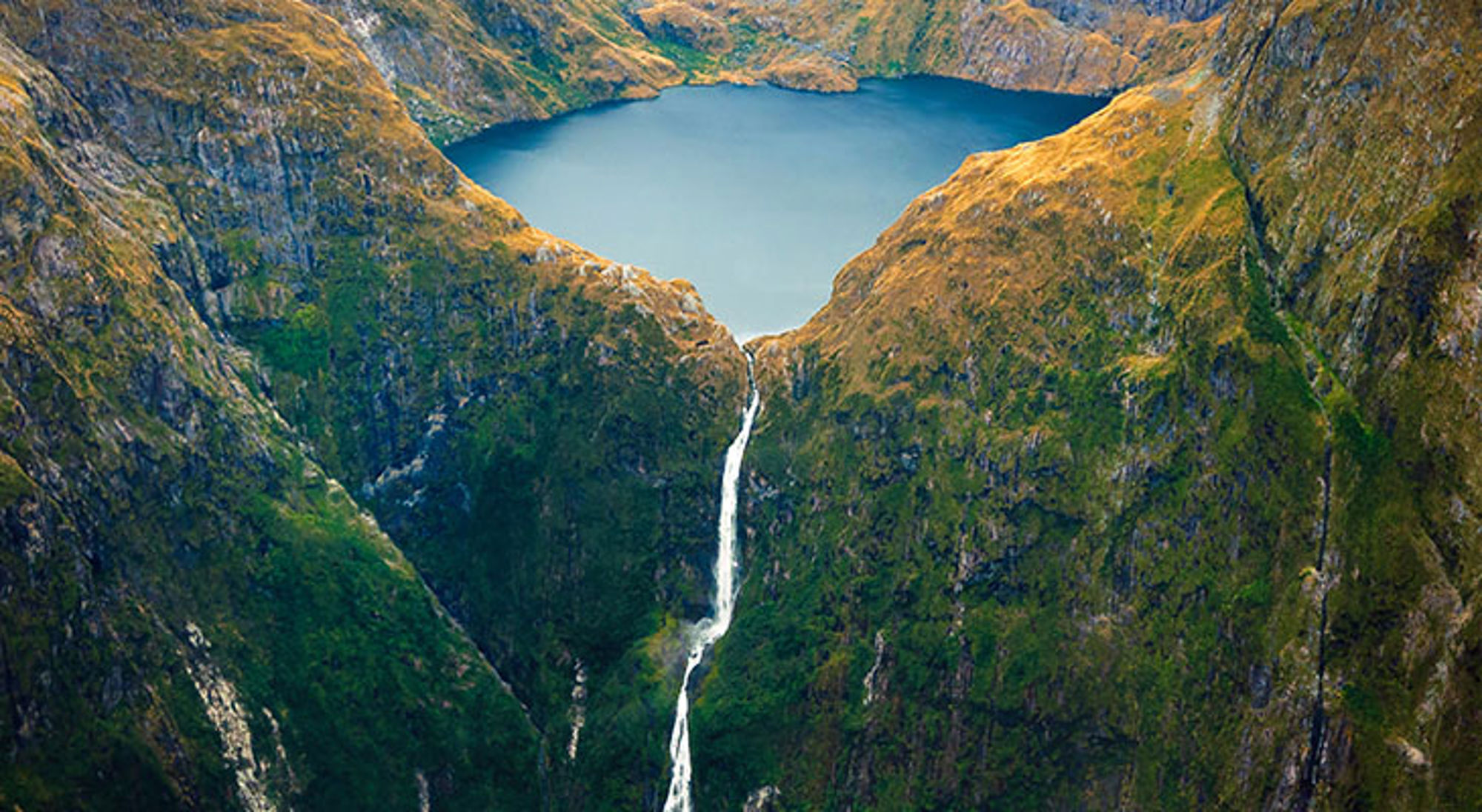 Sutherland Falls Bergmeer met waterval tussen steile groene bergwanden.