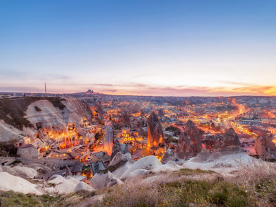 Avondpanorama van Göreme in Cappadocië met feeënschoorstenen en rotswoningen bij zonsondergang.