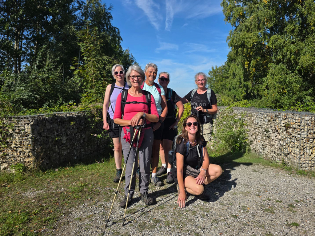 Wandelaars op de Dutch Mountain Trail, pauze op een zonnig bospad tussen stenen muren.