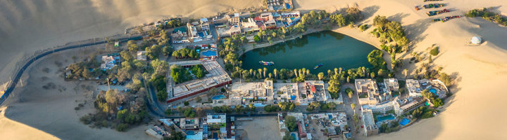 oase Huacachina met lagune, palmbomen en dorp omringd door zandduinen in Peru.