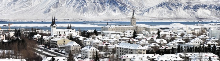 Sneeuwbedekt Reykjavik met Hallgrímskirkja en besneeuwde bergen op de achtergrond in de winter.