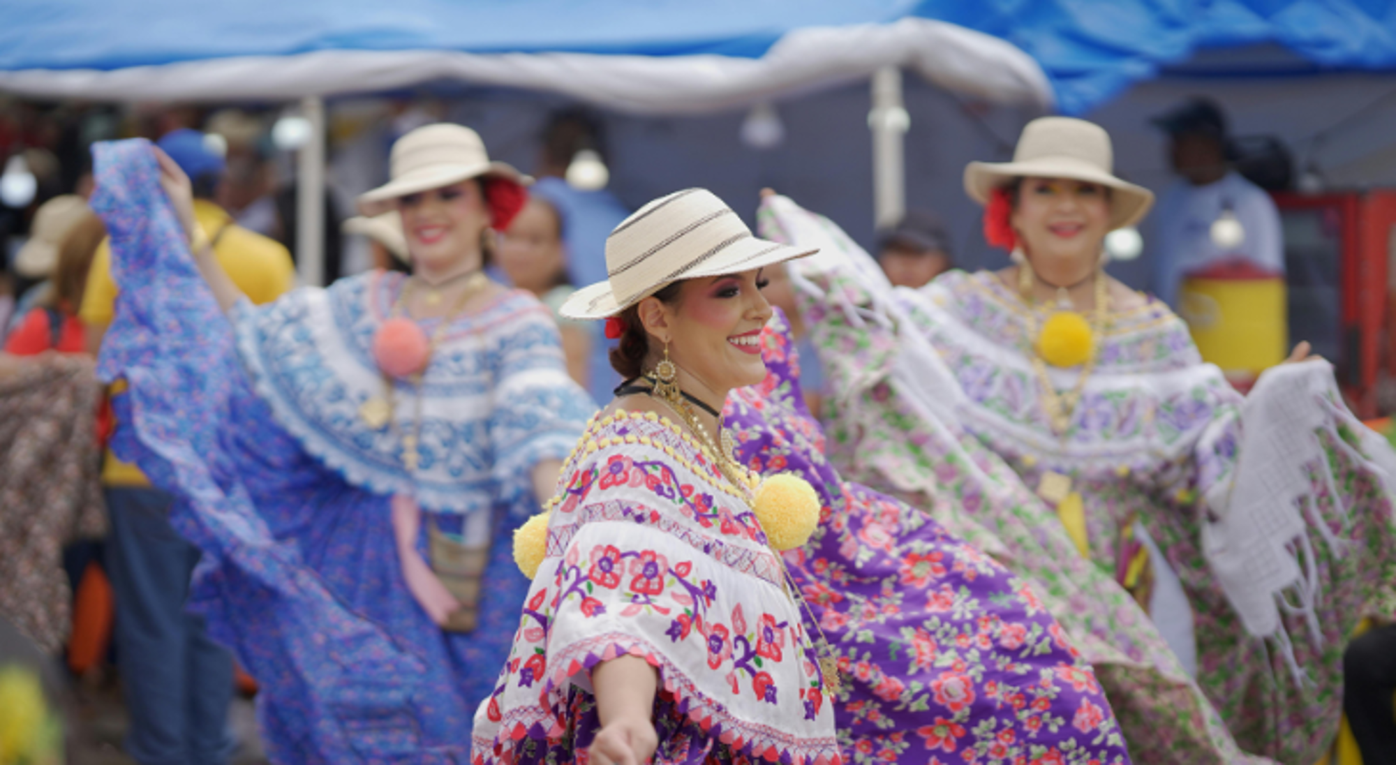 Vrouwelijke dansers in kleurrijke traditionele jurken tijdens een festivaloptreden.