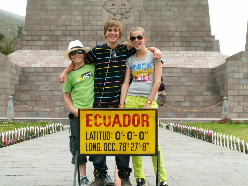 Gezin poseert bij het evenaarmonument in Ecuador tijdens een familiereis.