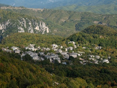 Uitzicht op bergdorp in de Pindos, Griekenland, omringd door groene heuvels en rotswanden.