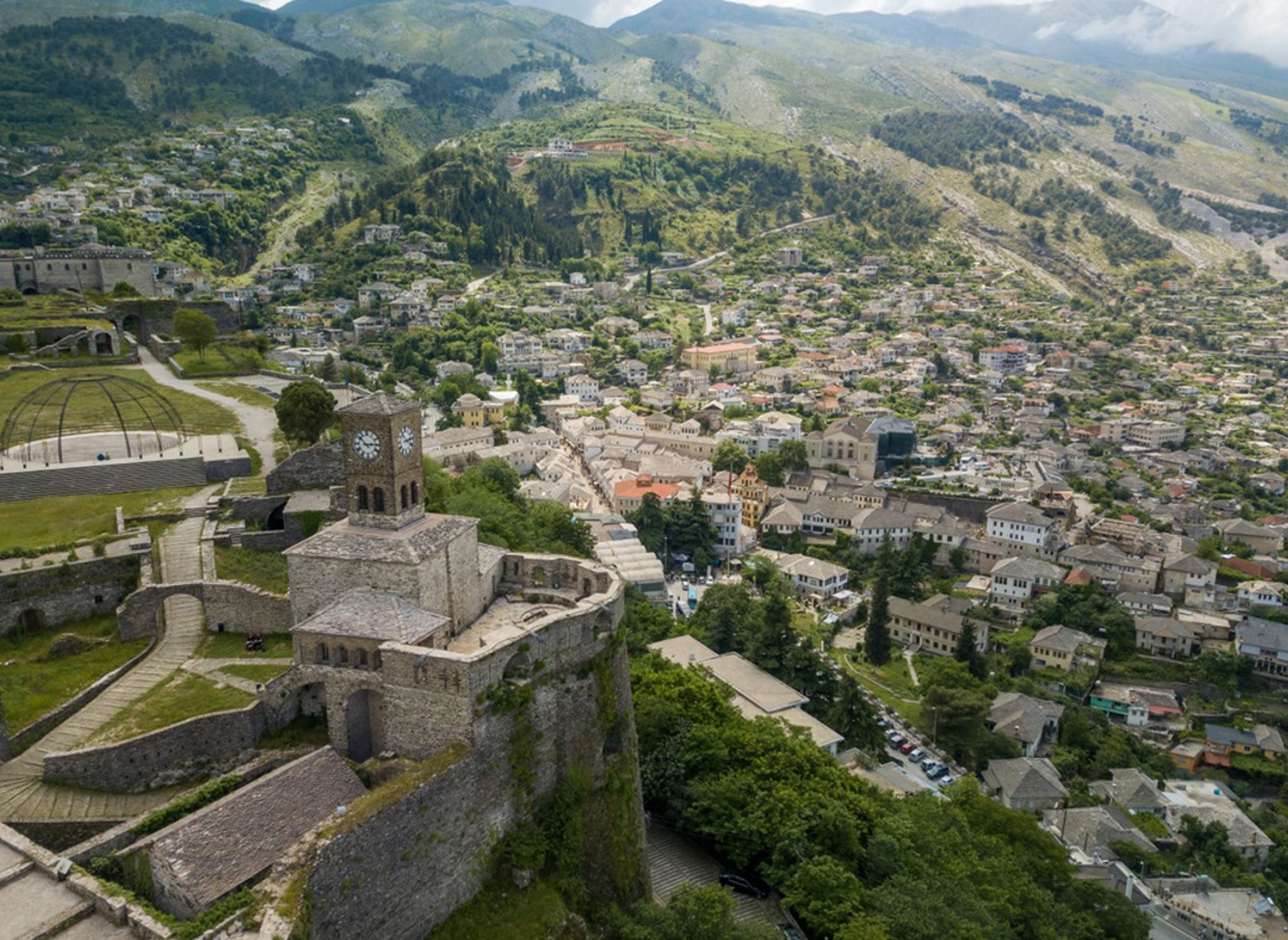Uitzicht op het kasteel van Gjirokastër en de oude stad in Albanië, met groene bergen op de achtergrond.